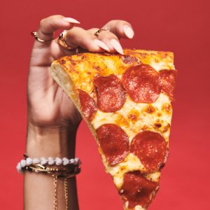 Hand holding a piece of Pizza Hut pizza.